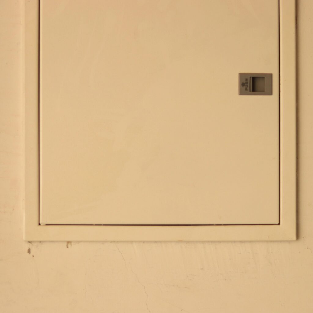White electricity box on a white wall with lid