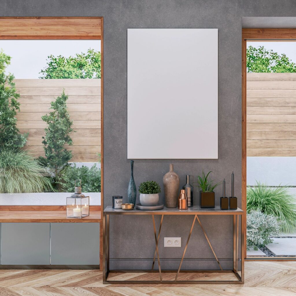 A chic, modern interior with console table, decoration, a white canvas with copy space on gray wall background and a nice view of a garden from large windows